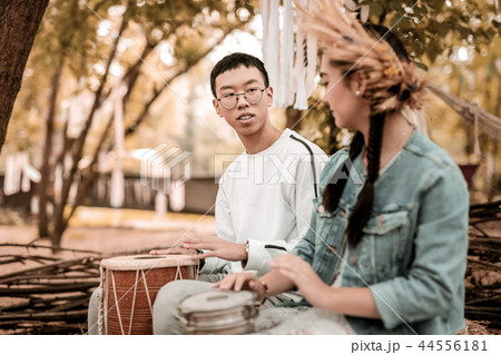 Delighted hippy making relaxing music in park 44556181