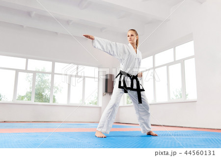Woman in white kimono with black belt training karate. Woman in white kimono with black belt training karate. 44560131