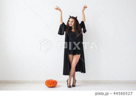 Halloween and holidays concept - Witch woman with Jack O'Lantern pumpkin over light background with Halloween and holidays concept - Witch woman with Jack O'Lantern pumpkin over light background with 44560527