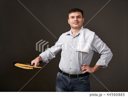 man posing with a pancake in a pan, white shirt 44560883