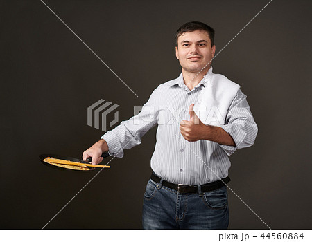 man posing with a pancake in a pan, white shirt 44560884