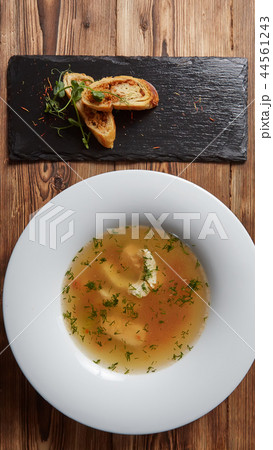 Beautiful presentation of the fish soup in a white plate, with bread on a wooden background Beautiful presentation of the fish soup in a white plate, with bread on a wooden background 44561243