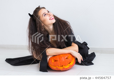 Halloween and masquerade concept - Beautiful young woman posing with Pumpkin Jack-o'-lantern. 44564757