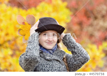 Smiling girl in hat in autumn park. Bright foliage 44570738