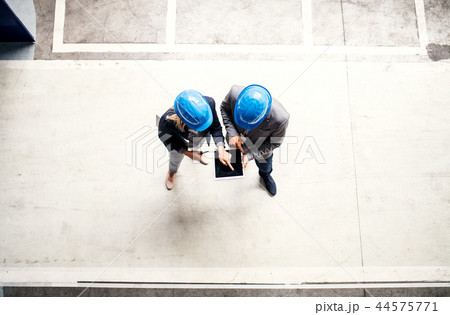 A top view of an industrial man and woman engineer with tablet in a factory, working. A top view of an industrial man and woman engineer with tablet in a factory, working. 44575771