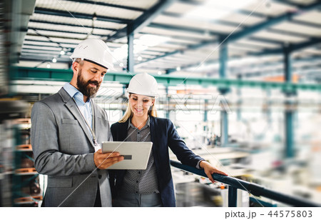 A portrait of an industrial man and woman engineer with tablet in a factory, working. A portrait of an industrial man and woman engineer with tablet in a factory, working. 44575803