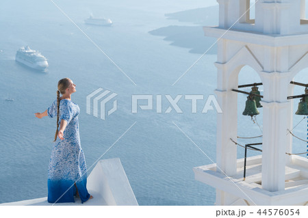 Happy woman in white and blue dress enjoying her holidays on Santorini, Greece. View on Caldera and Happy woman in white and blue dress enjoying her holidays on Santorini, Greece. View on Caldera and 44576054