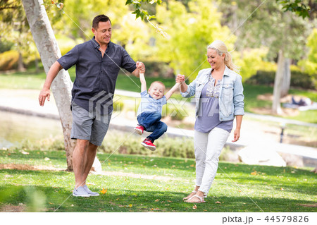 Young Mother and Father Swingging Their Son At The Park Young Mother and Father Swingging Their Son At The Park 44579826