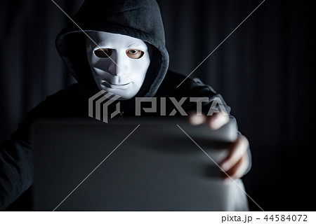 Hacker man in white mask holding laptop Hacker man in white mask holding laptop 44584072