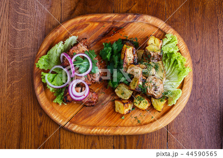 Board with barbecue and baked potatoes on a wooden table Board with barbecue and baked potatoes on a wooden table 44590565