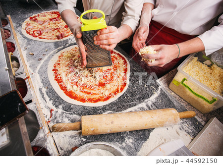 Adding cheese to pizza. Stages of cooking pizza. 44592150
