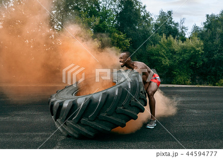 Handsome muscular man flipping big tire outdoor. 44594777
