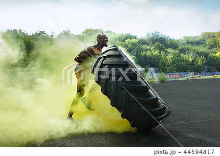 Handsome muscular man flipping big tire outdoor. Handsome muscular man flipping big tire outdoor. 44594817