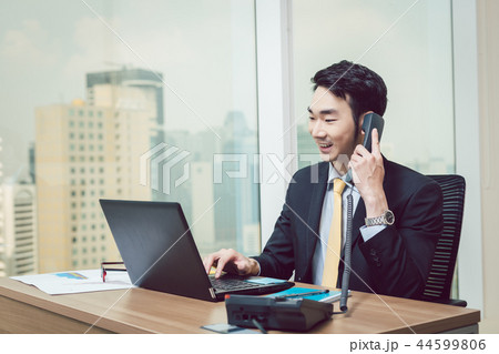 Smiling young businessman working on laptop Smiling young businessman working on laptop 44599806
