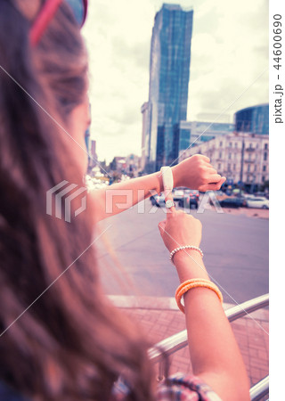 Dark-haired woman wearing ring and bracelets on her right hand checking time Dark-haired woman wearing ring and bracelets on her right hand checking time 44600690