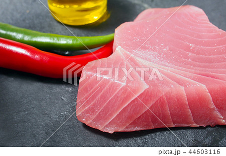 Fresh and raw tuna steak with chili peppers and ol 44603116