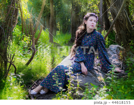 sad woman sits on a stone by a tree in forest sad woman sits on a stone by a tree in forest 44618155