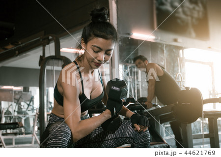 Asian woman lifting dumbbell at gym and man 44621769