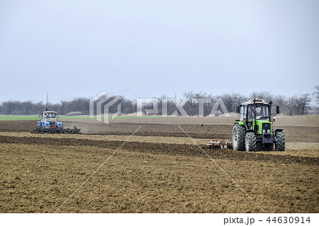 Lush and loosen the soil on the field before sowing. The tractor plows a field with a plow 44630914