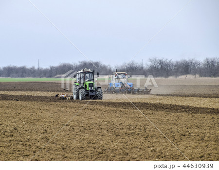 Lush and loosen the soil on the field before sowing. The tractor plows a field with a plow 44630939