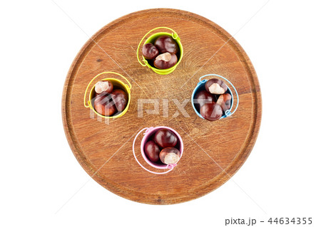 Colorful buckets with chestnuts on wooden plate 44634355