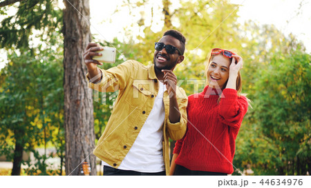 African American guy is taking selfie with female friend holding smartphone and posing with African American guy is taking selfie with female friend holding smartphone and posing with 44634976