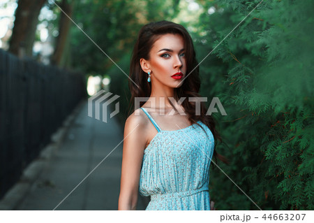 Woman walking in the park in a turquoise dress Woman walking in the park in a turquoise dress 44663207