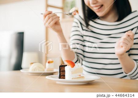 たくさんのケーキを食べる若い日本人女性の写真素材