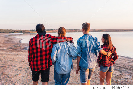 friends on beach together walking during sunset 44667118