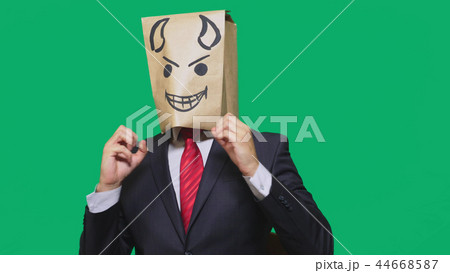 concept of emotion, gestures. a man with a package on his head, with a painted smiley angry, sly concept of emotion, gestures. a man with a package on his head, with a painted smiley angry, sly 44668587