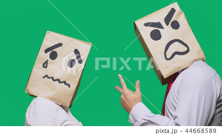 The concept of emotions and gestures. Two people in paper bags with smileys. Aggressive smiley The concept of emotions and gestures. Two people in paper bags with smileys. Aggressive smiley 44668589