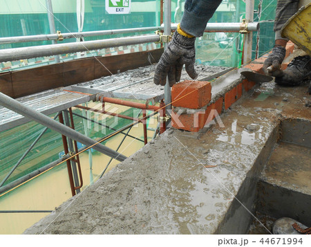 Workers laying brick to form brick wall 44671994