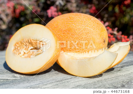 Whole and sliced melon on wooden table outdoors 44673168