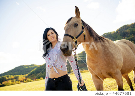 A Woman with her horse at sunset, autumn outdoors scene 44677681