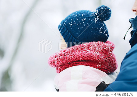 child  playing in the snow / the girl in warm sports clothes is playing with snow on a winter walk. Warm woolen hat, down jacket. Concept of a happy baby walk. 44680176