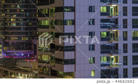 Windows of the multi-storey building of glass and steel lighting inside and moving people within timelapse Windows of the multi-storey building of glass and steel lighting inside and moving people within timelapse 44682602