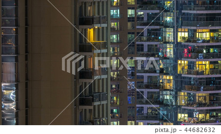 Windows of the multi-storey building of glass and steel lighting inside and moving people within timelapse 44682632