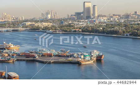 Dubai creek landscape timelapse with boats and ship in port and modern buildings in the background during sunset Dubai creek landscape timelapse with boats and ship in port and modern buildings in the background during sunset 44682944