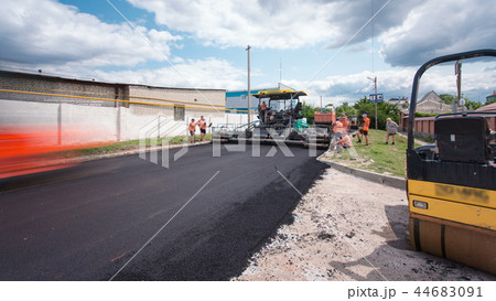 A paver finisher, asphalt finisher or paving machine placing a layer of asphalt during a repaving construction project timelapse A paver finisher, asphalt finisher or paving machine placing a layer of asphalt during a repaving construction project timelapse 44683091