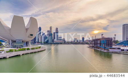 Futuristic architecture flower shape design of the Art Science museum at the foreground timelapse and skyscrapers skyline city of Singapore. Futuristic architecture flower shape design of the Art Science museum at the foreground timelapse and skyscrapers skyline city of Singapore. 44683544
