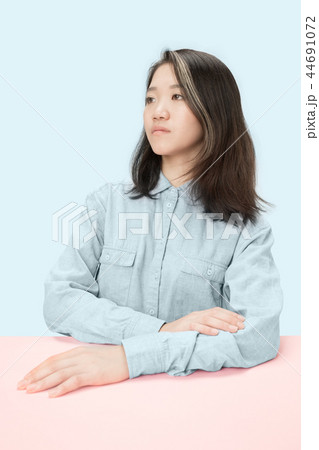 The serious business woman sitting and looking at left against blue background. 44691072