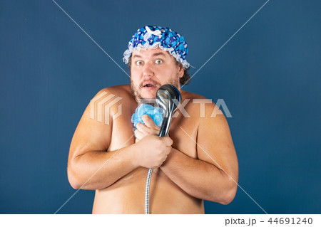 Funny fat man in blue cap sing in the shower 44691240