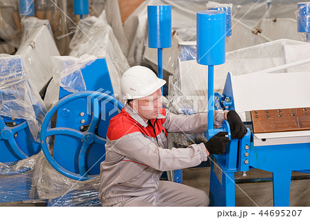 Production of ventilation and drainpipe. Worker unpacks the machine in the warehouse. Tool and 44695207