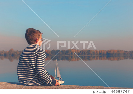Child playing with sailing boat in beautiful light Child playing with sailing boat in beautiful light 44697747