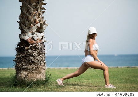 Beautiful woman is doing streching exercises on the beach Beautiful woman is doing streching exercises on the beach 44699088