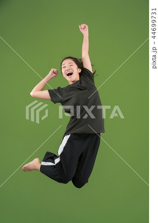 Freedom in moving. Pretty young woman jumping against green background 44699731