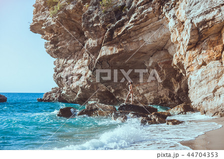 Beautiful young woman on wild rocky beach. 44704353