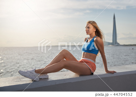 Sports woman sitting along the sea on waterfront. Sports woman sitting along the sea on waterfront. 44704552