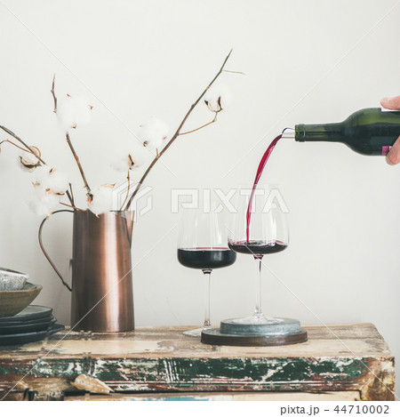 Red wine pouring from bottle in man's hand, square crop 44710002