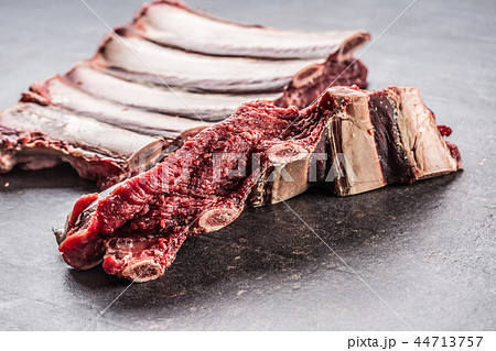 Portion of raw beef ribs on dark butcher board 44713757